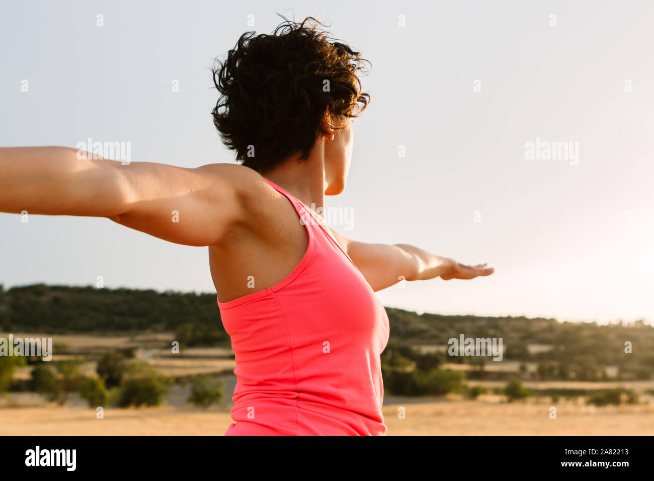 Shot of young curly woman doing yoga in a rural landscape at sunset Stock Photo