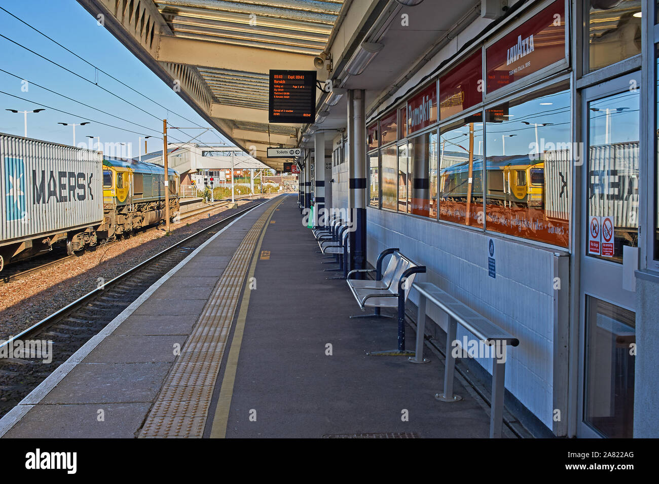 An inter-modal freightliner train pulled by a Class  66 locomotive waits at a red signal in Peterborough station. Stock Photo