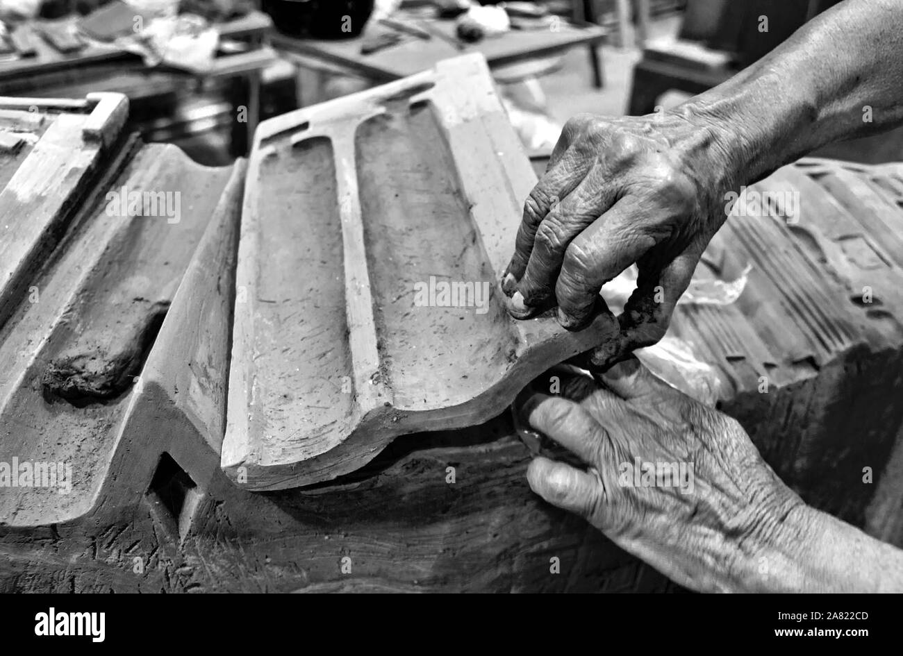 The artist uses his hands to make clay-shaped tiles for houses. Stock Photo