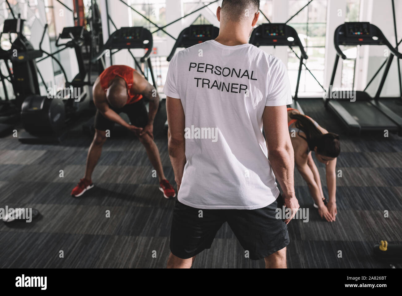 back view of personal trainer supervising multicultural athletes ...