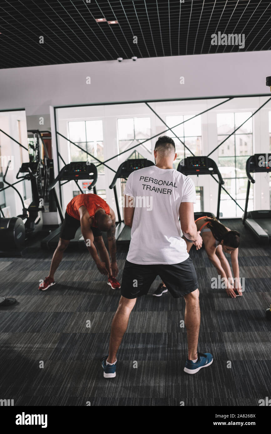 back view of personal trainer supervising multicultural athletes ...