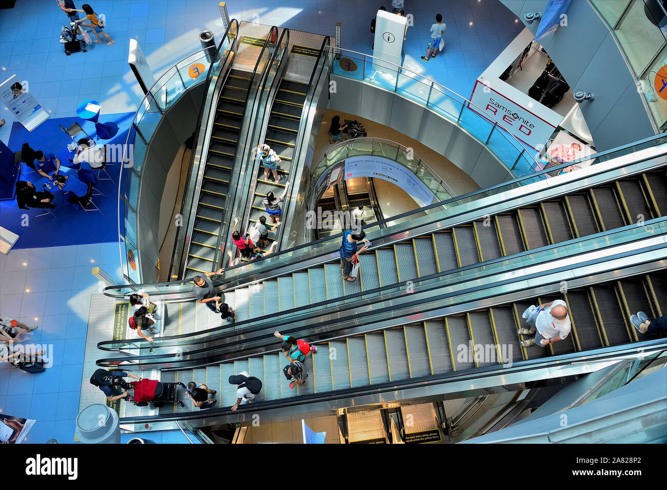 Singapore - September 29 2019: Aerial view of modern escalator shaft at Vivo City shopping centre with shoppers Stock Photo