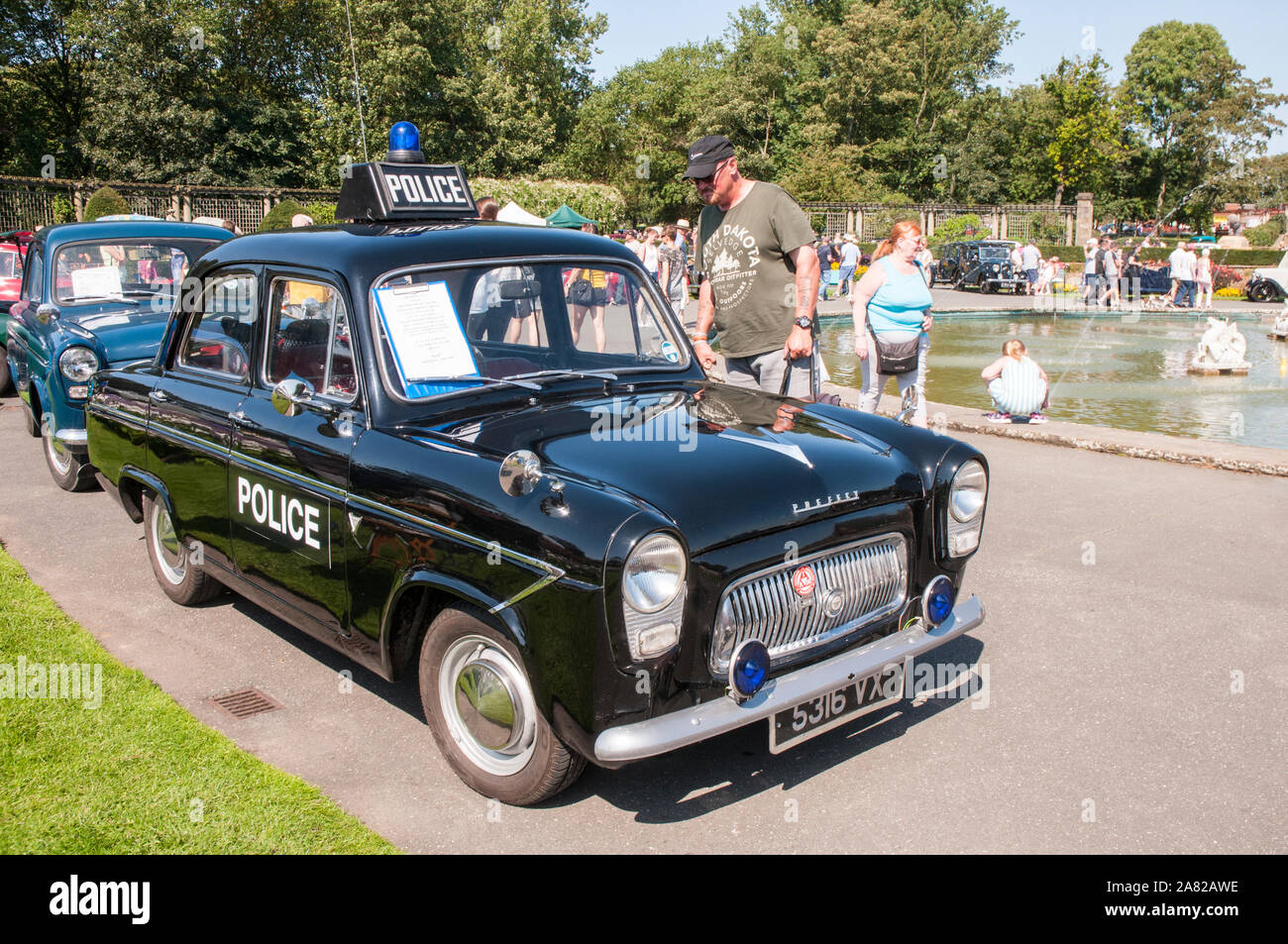 Man looking at a 1960 107E Ford Prefect 997cc Police car as used by Essex police. At the Classic Car Show Stanley Park Blackpool Lancashire England UK Stock Photo