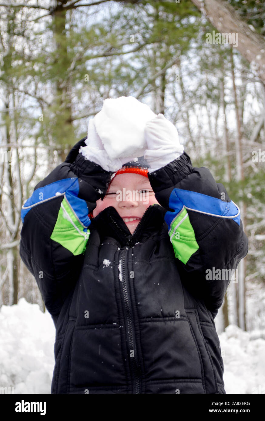 with arms raised, this child is ready to throw a snow ball at you Stock Photo