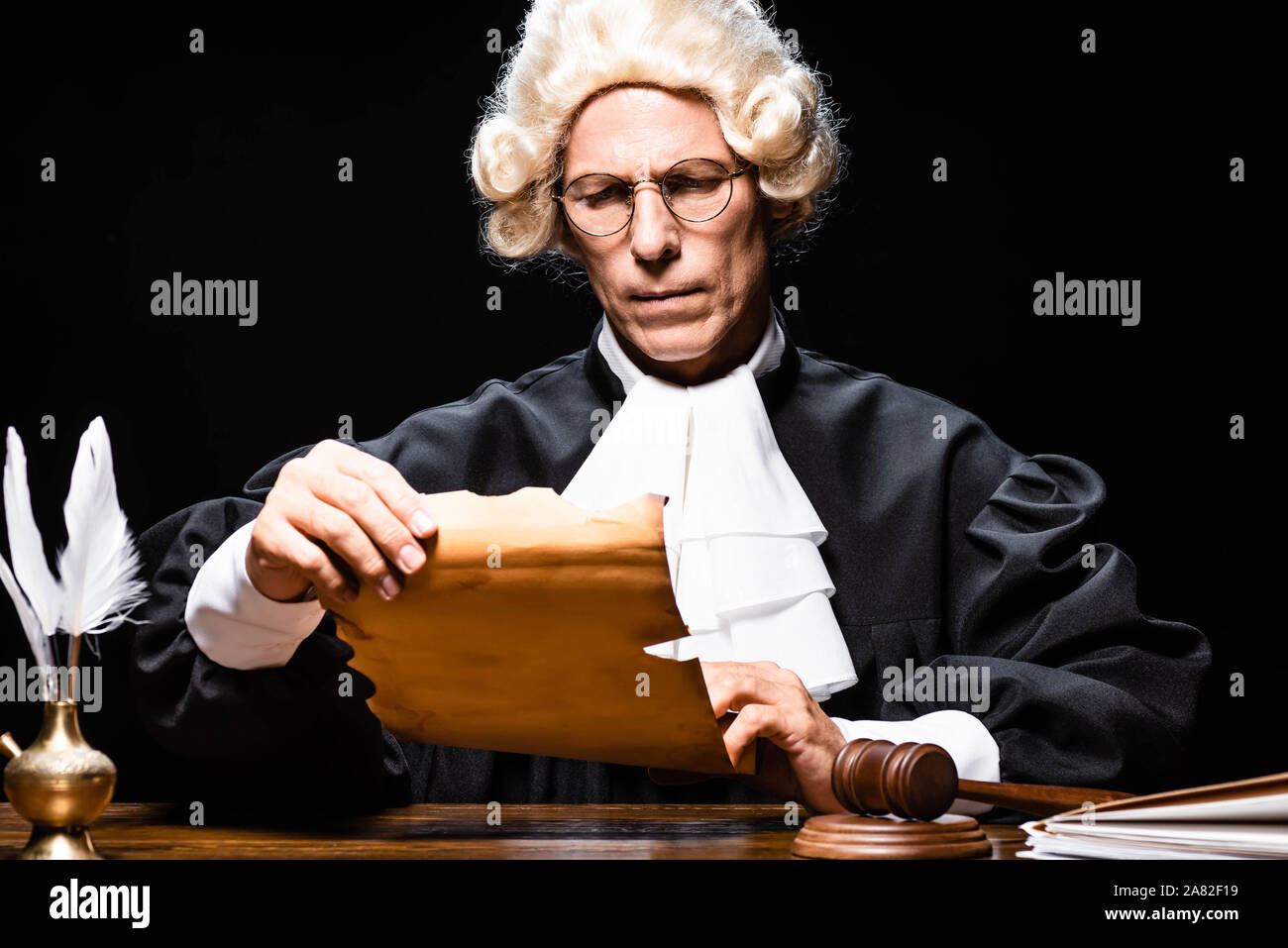 judge in judicial robe and wig sitting at table and reading document ...