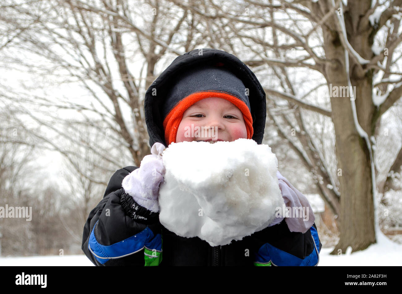 child outdoors holding a very large snow ball Stock Photo