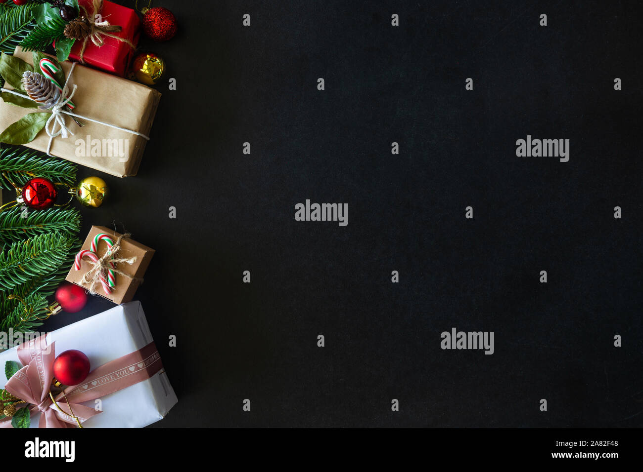 Holiday Christmas card background with festive decoration ball, stars, snowflakes, gift box, pine cones on a black background from Flat lay, top view. Stock Photo