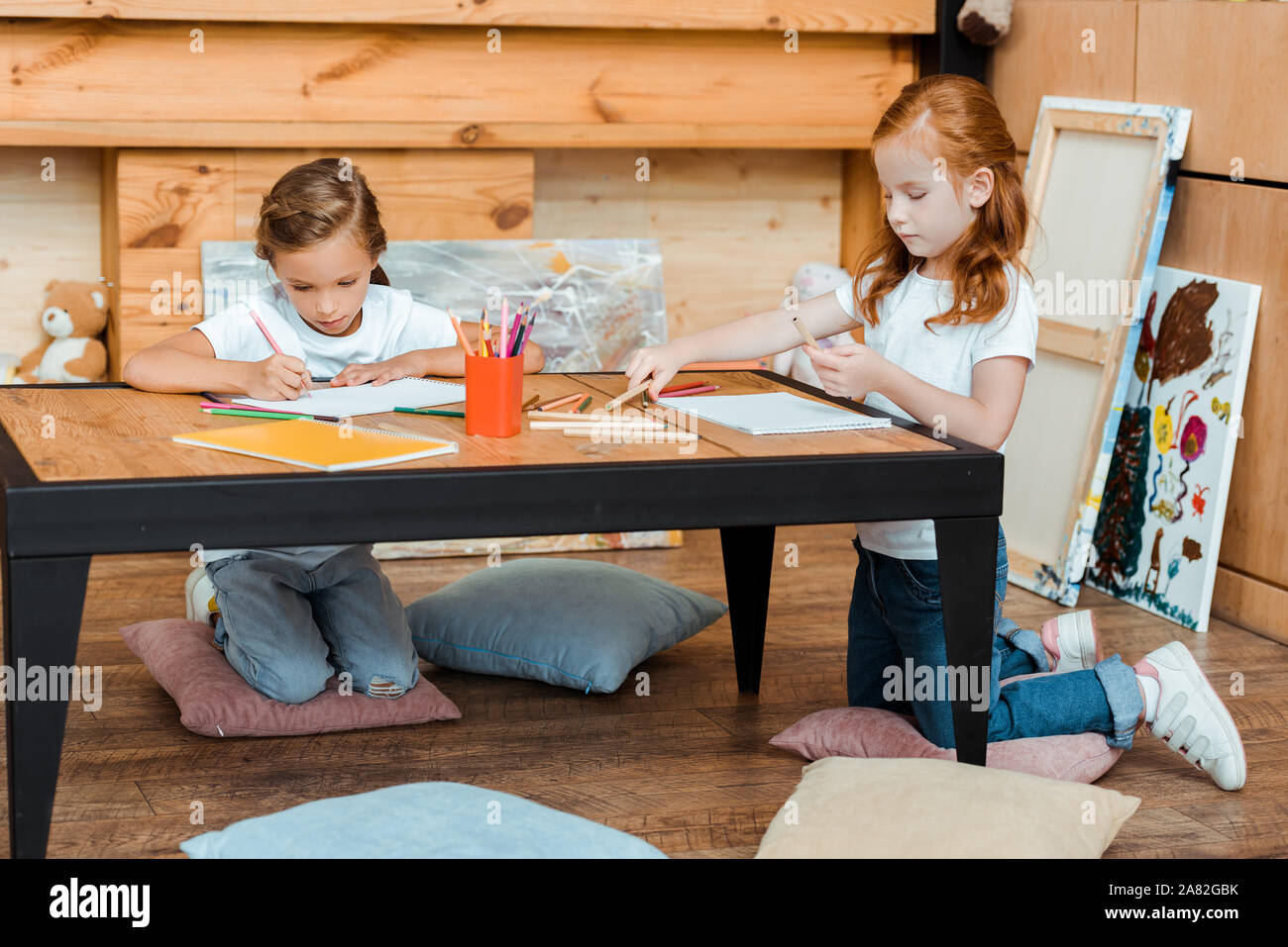 cute kids drawing on papers while sitting on pillows Stock Photo