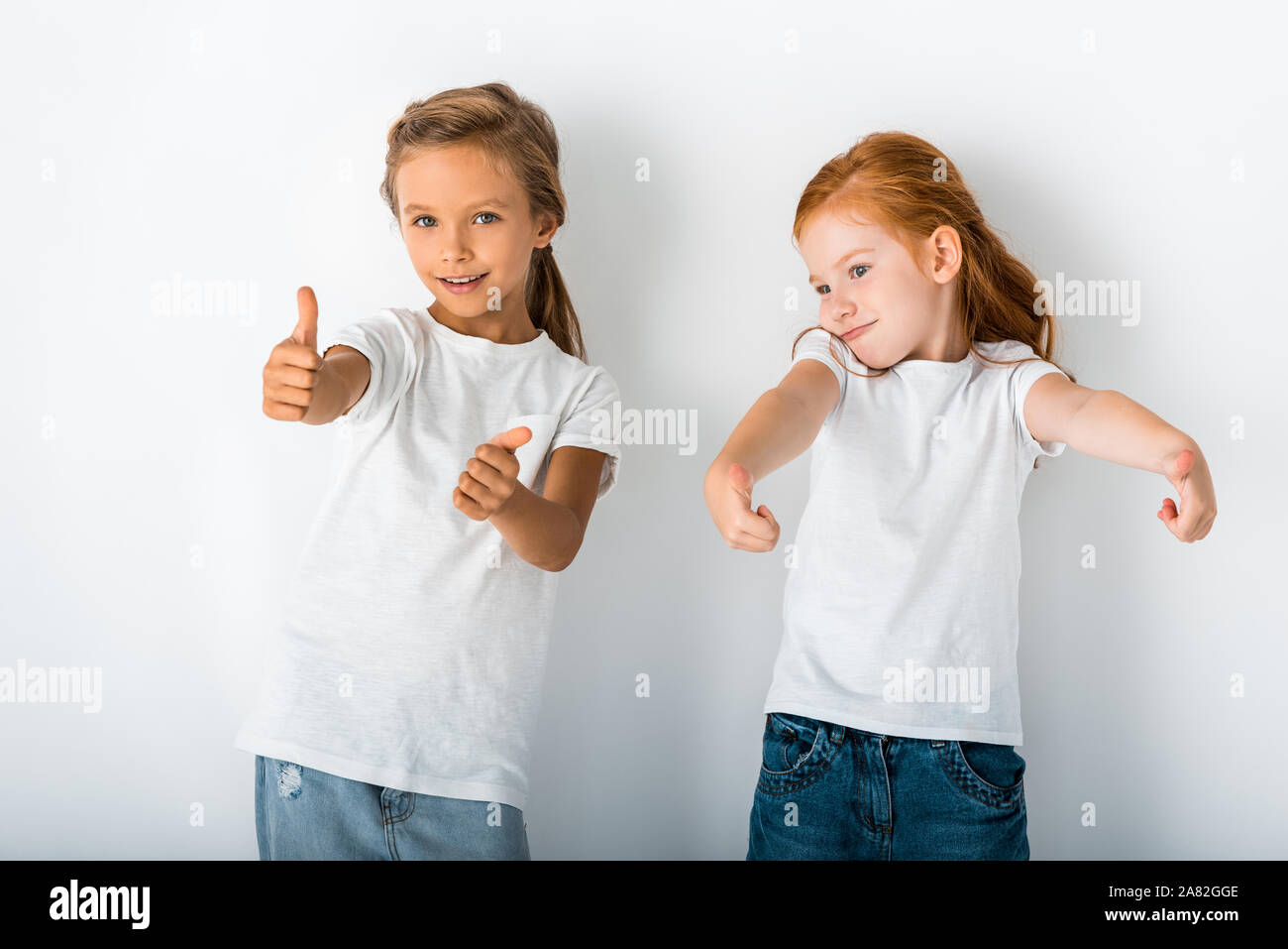 Adorable Kids Smiling And Showing Thumbs Up On White Stock Photo