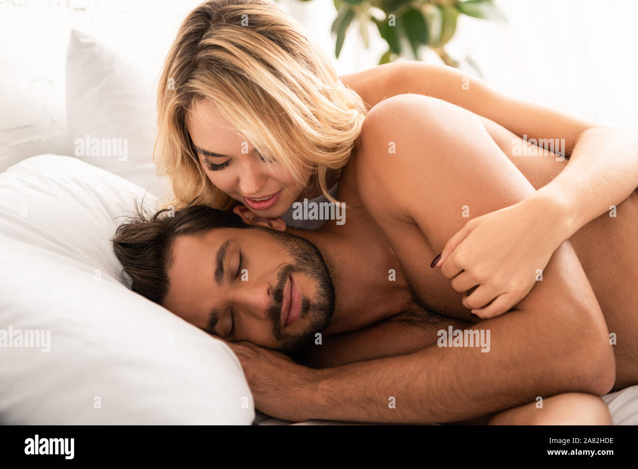 woman hugging her sleeping boyfriend in bed in the morning Stock Photo