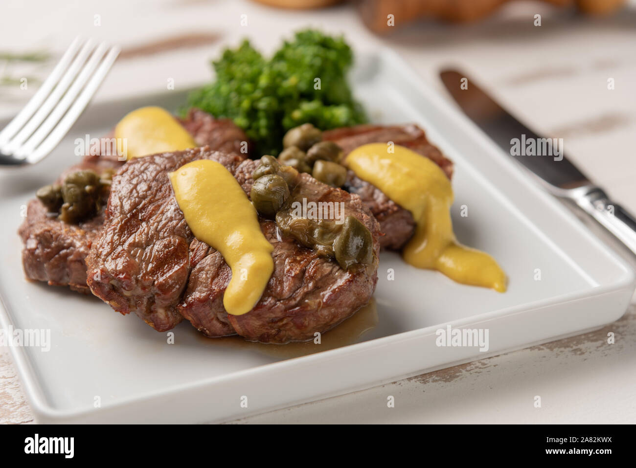 Filet mignon with caper and mustard sauce, broccoli, pepper grinder on