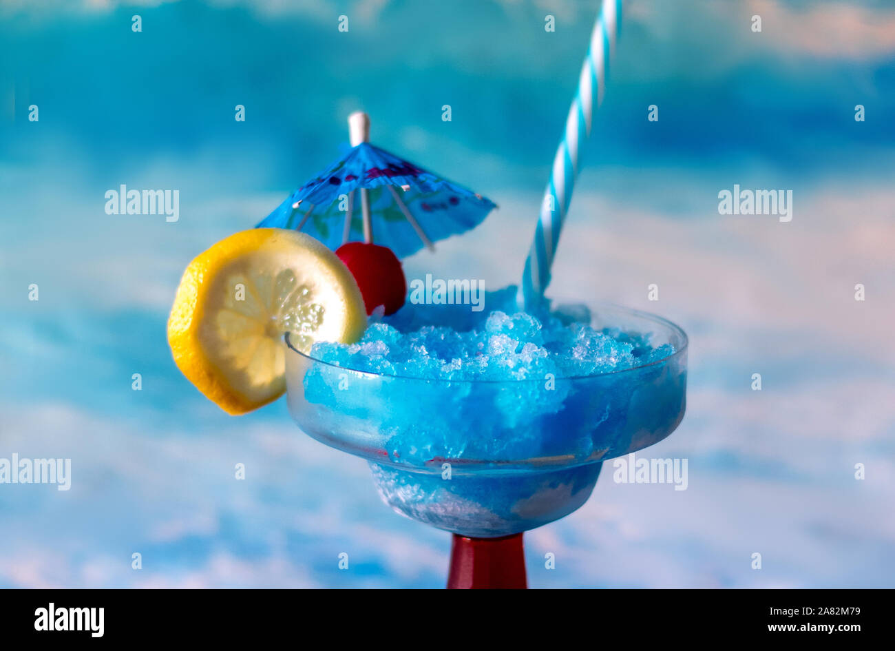 colorful blue cocktail with a lemon and cherry garnish and blue drink