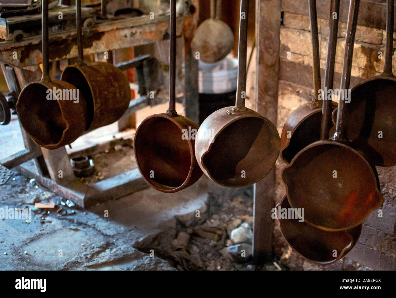 crucible ladles hang from a rack inside a glass factory in North ...
