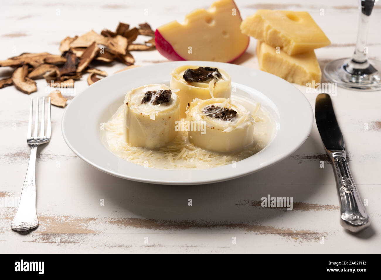 Homemade rondelli with four cheese and mushuroom sauce in white plate on rustic white wooden table background, soft light Stock Photo