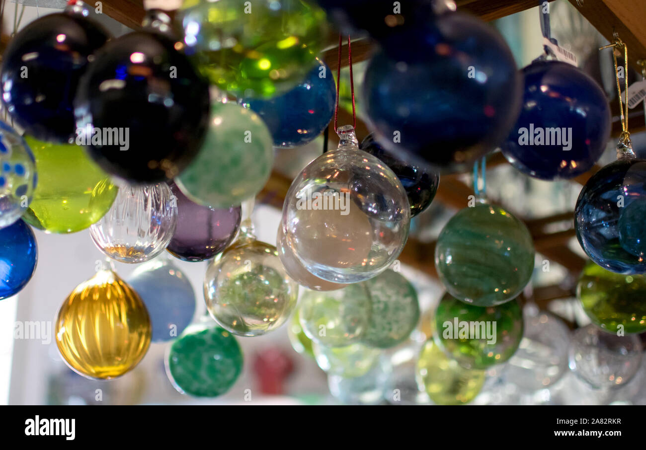Delicate glass balls in many colors, hang from a display at an art shop