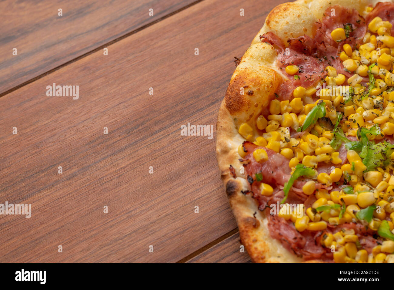 Pepperoni  and corn pizza on a wooden background. Top view. Flat view. Stock Photo