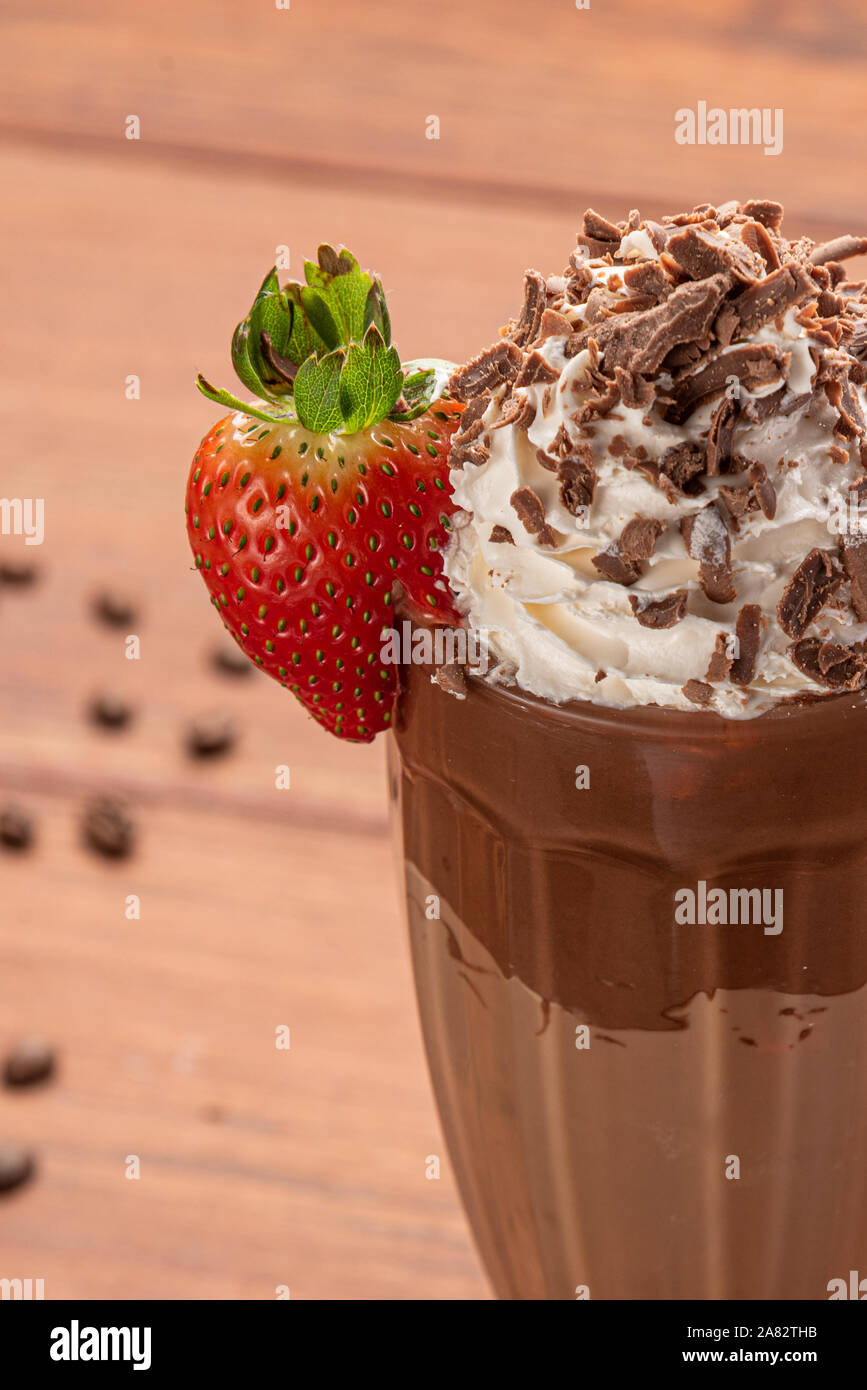 Cold coffee drink frappe (frappuccino), with whipped cream and chocolate nibs, with grains of coffee on wooden background Stock Photo