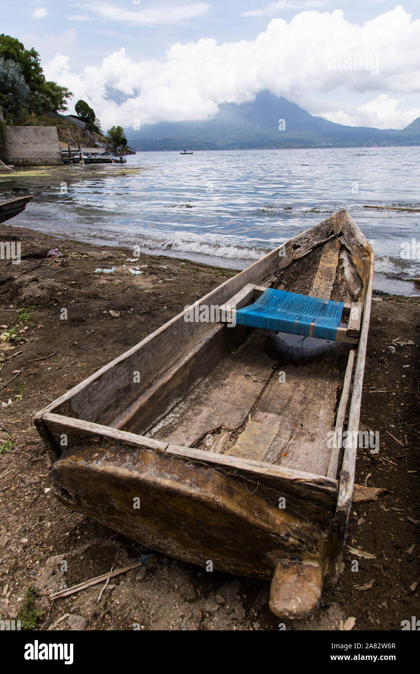 A cayuco or fishing boat on the shore of Lake  Atitilan at San Antonio Palopó, Guatemala with  a fishing boat on Lake Atitlan and the San Pedro Volcan Stock Photo