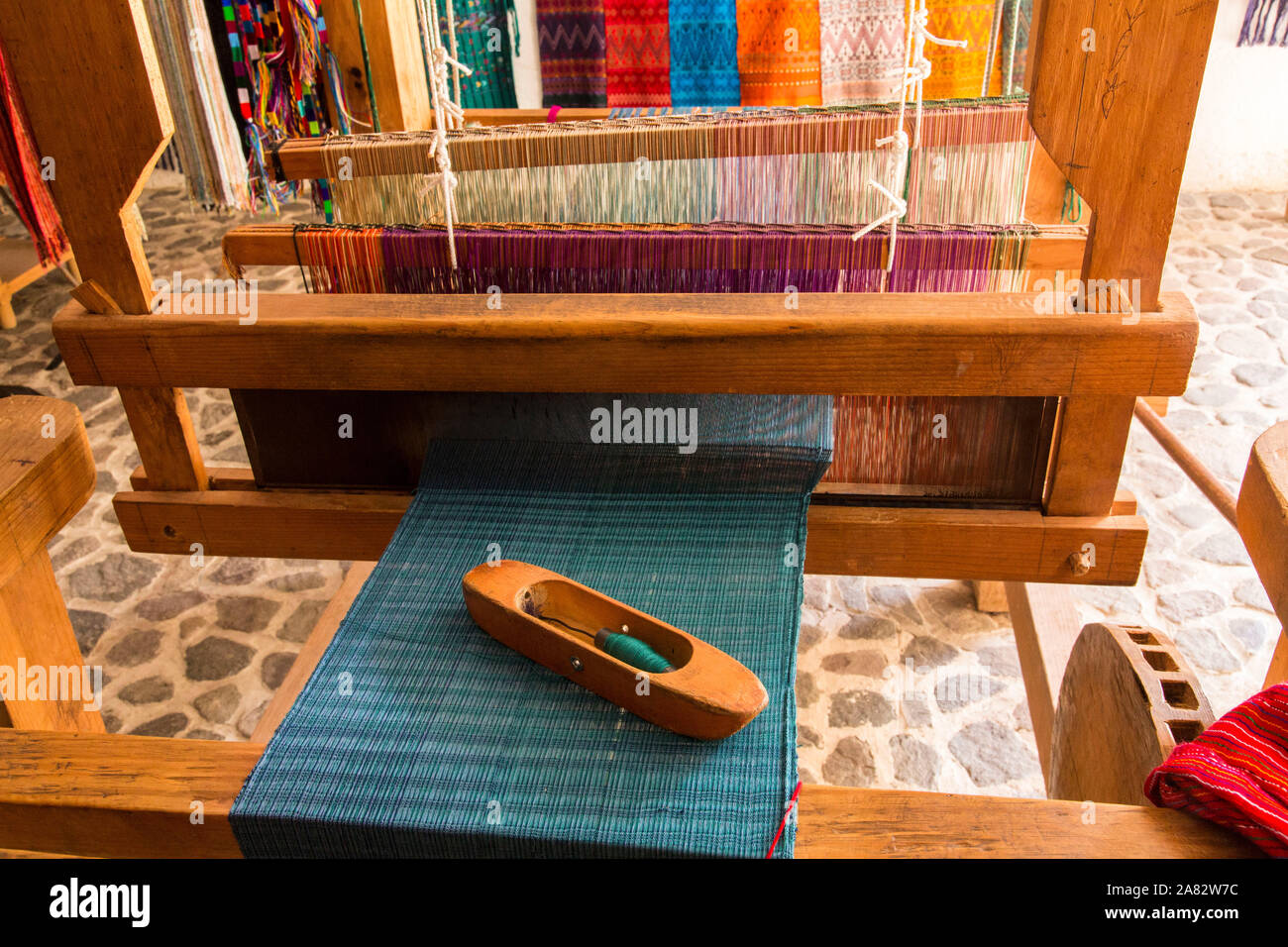 Detail of a wooden weaving shuttle on the woven cloth on a foot-operated wooden loom in San Antonio Palopó, Guatemala. Stock Photo