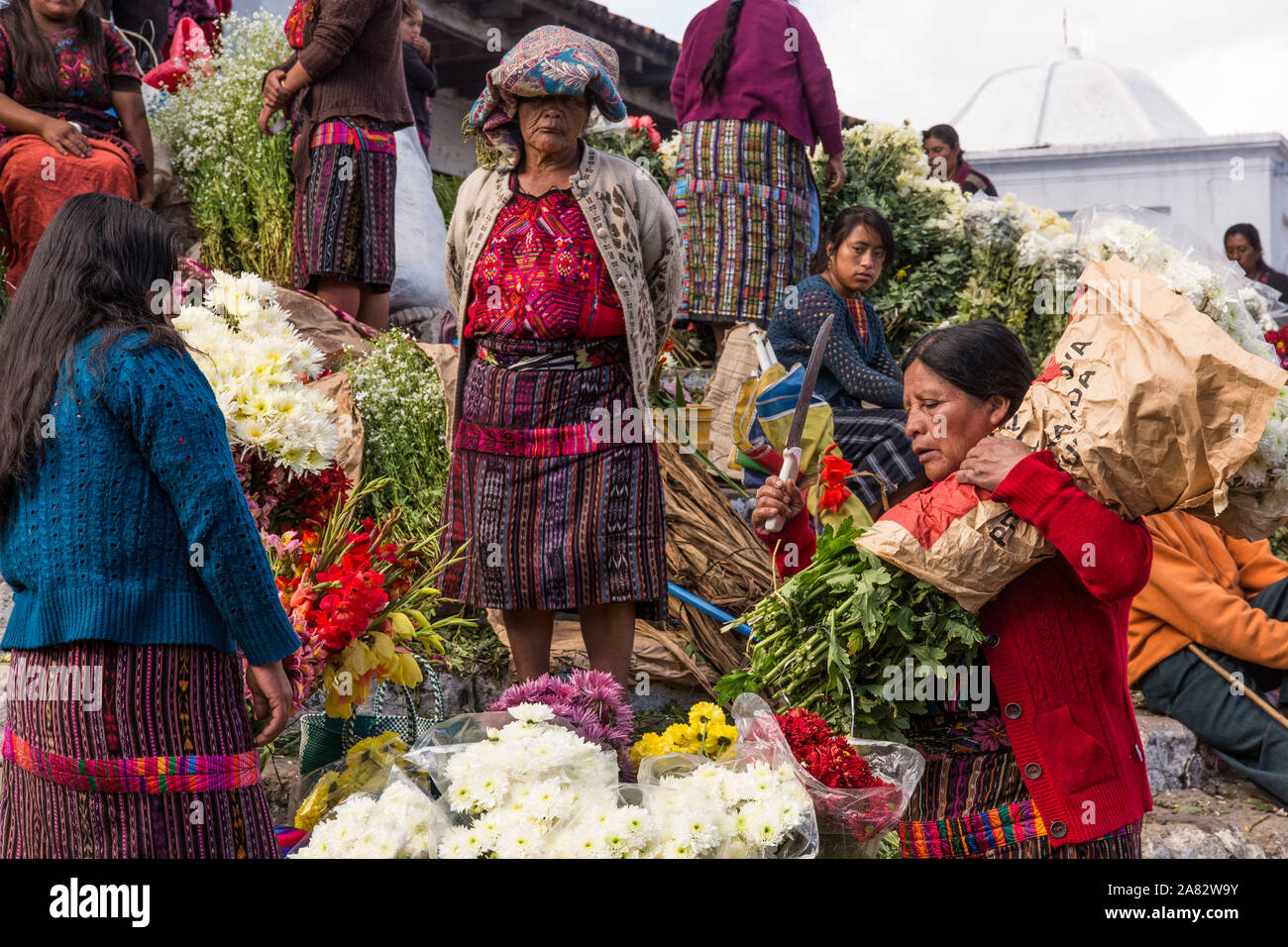 Quiche Mayan women in traditional dress selling flowers on the steps of the Church of Santo Tomas in Chichicastenango, Guatemala. Stock Photo