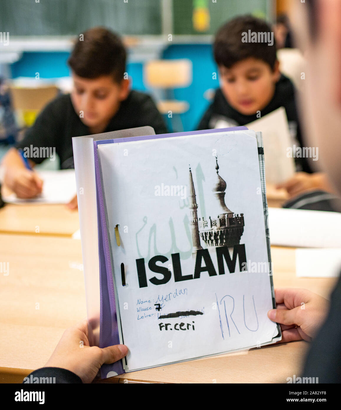 28 October 2019, Hessen, Frankfurt/Main: The pupil Merdan opens his self-designed folder during Islamic lessons in a seventh grade at the Ernst Reuter School in Frankfurt. The state of Hesse has been arguing for months about cooperation with the controversial Turkish mosque association Ditib in Islamic religious education. In order to be prepared for Ditib's withdrawal, the country has been offering the new subject of Islamic instruction since this school year in sole state responsibility for pupils in grade seven. Photo: Frank Rumpenhorst/dpa Stock Photo