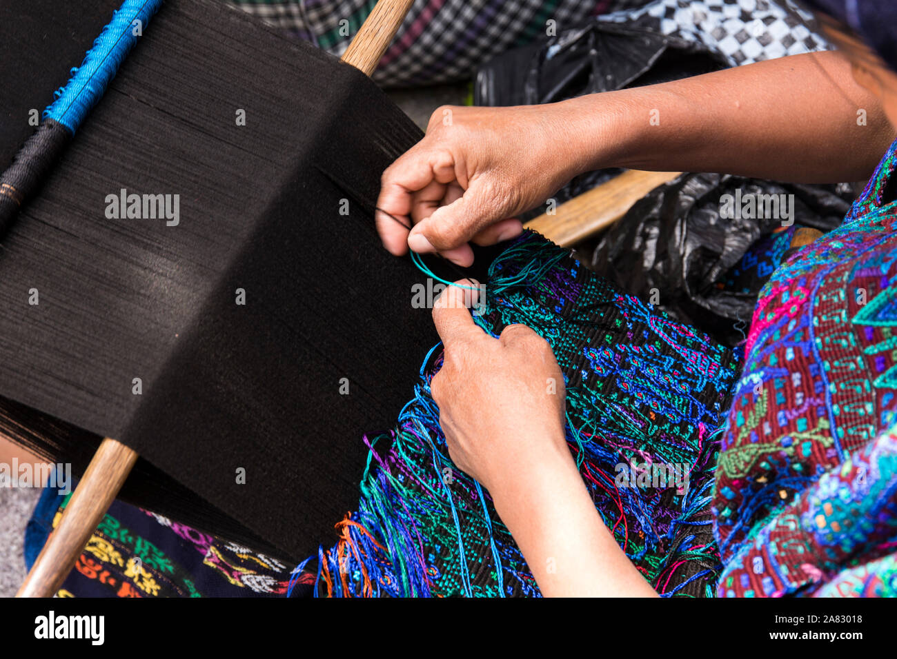 A Mayan woman in traditional dress sitting on the ground and weaving on a backstrap loom in Santa Catarina Palopo, Guatemala. Stock Photo