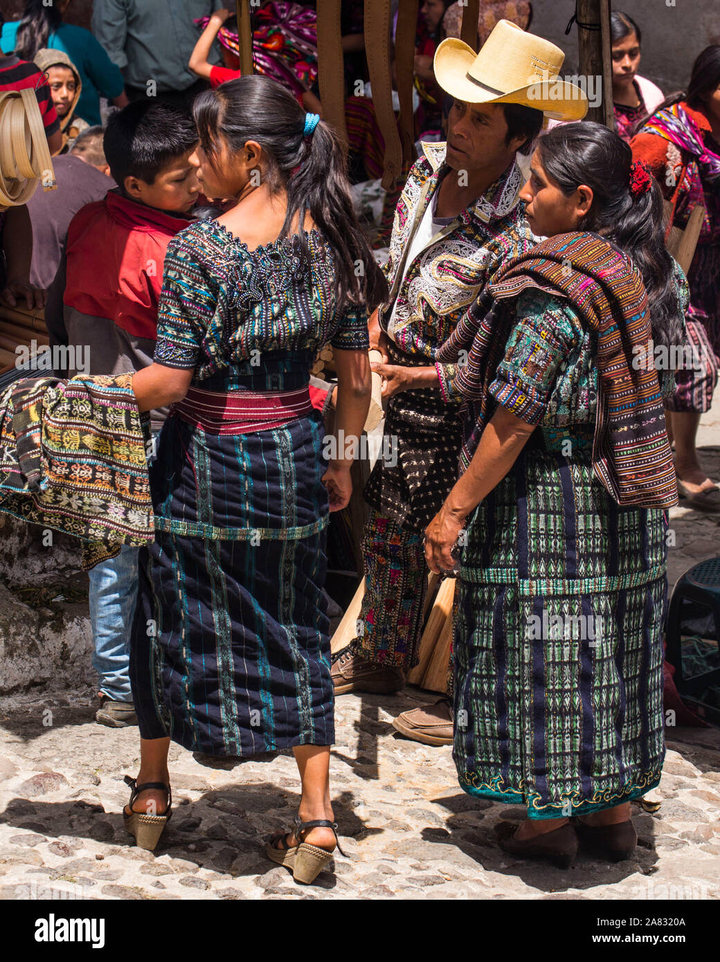 A Mayan family, father, mother, son and daughter, in the traditional dress of  Sololá, shop at the Sunday market in Chichicastenango, Guatemala. Stock Photo