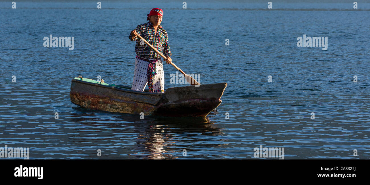 Mayan man in the traditional dress of San Pedro la Laguna paddles a cayuco in early morning light on Lake Atitlan, Guatemala.  Standing. Stock Photo