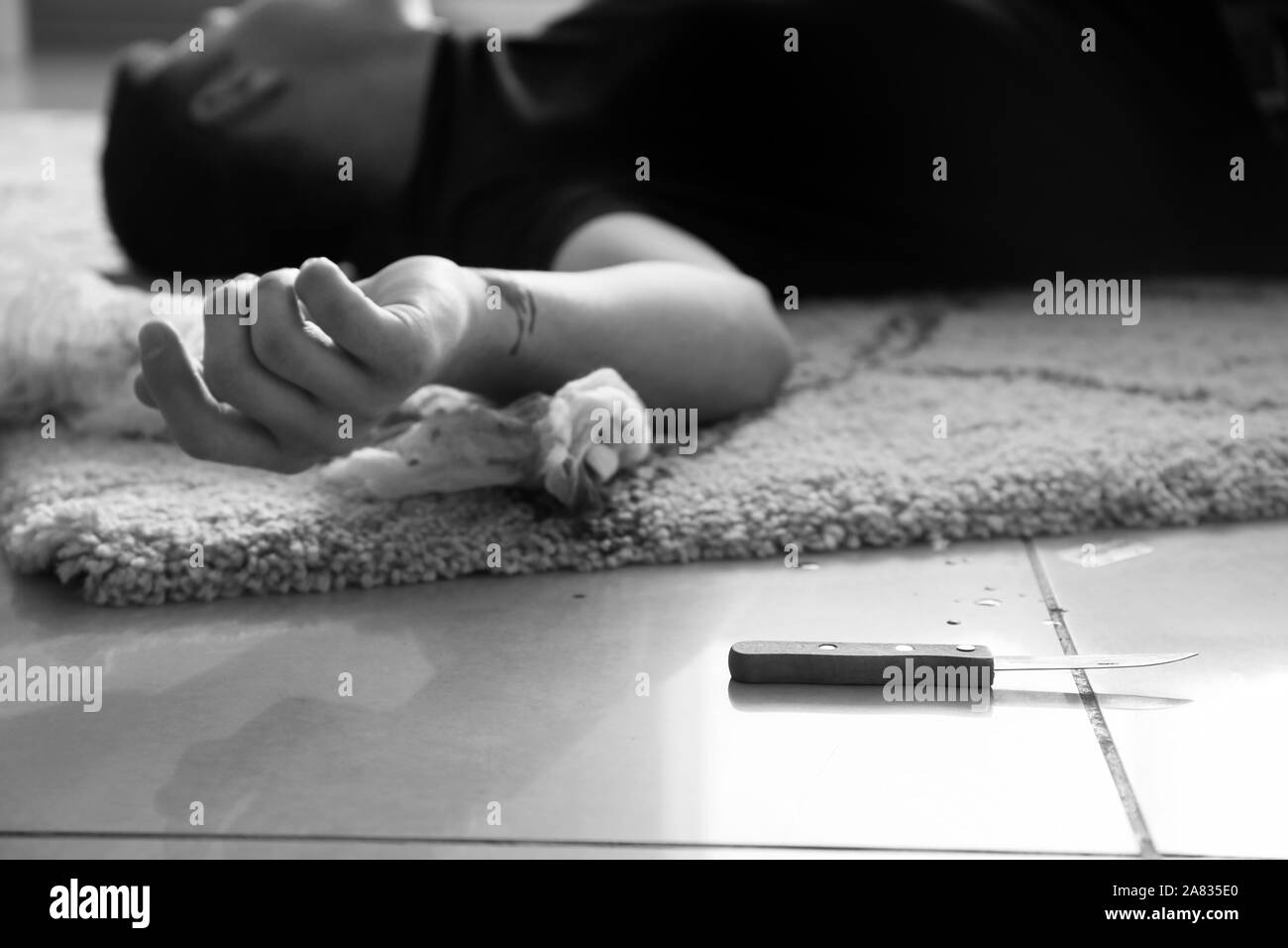Black and white photo of dead man with cut veins lying on floor. Suicide concept Stock Photo