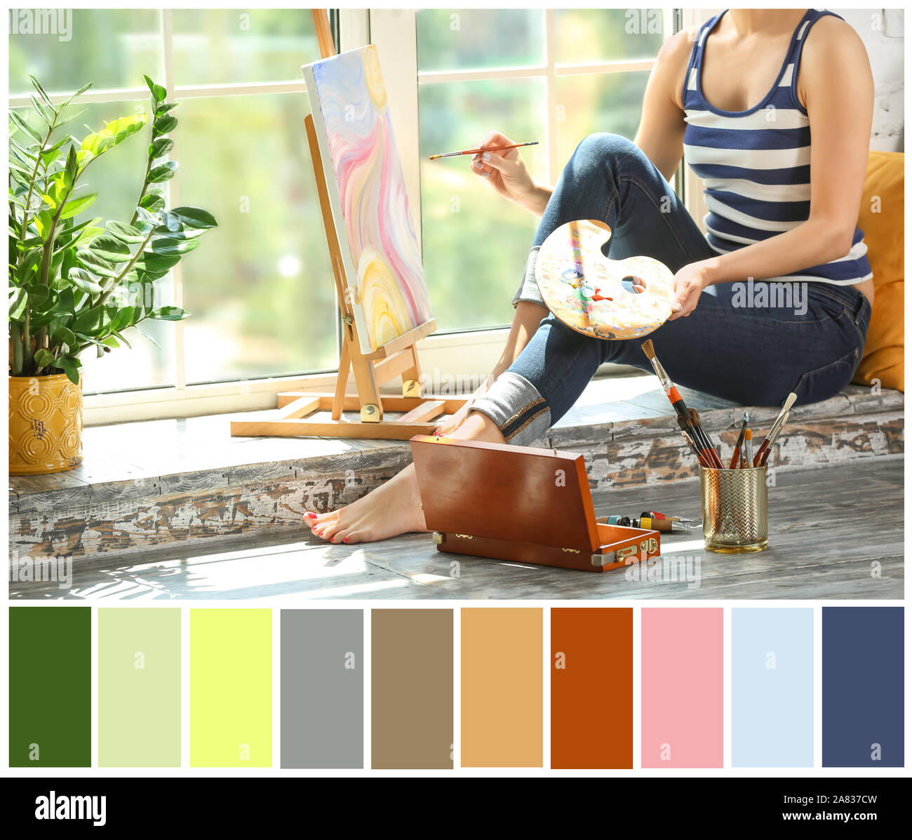 Female artist painting picture while sitting on windowsill in workshop. Different color patterns Stock Photo