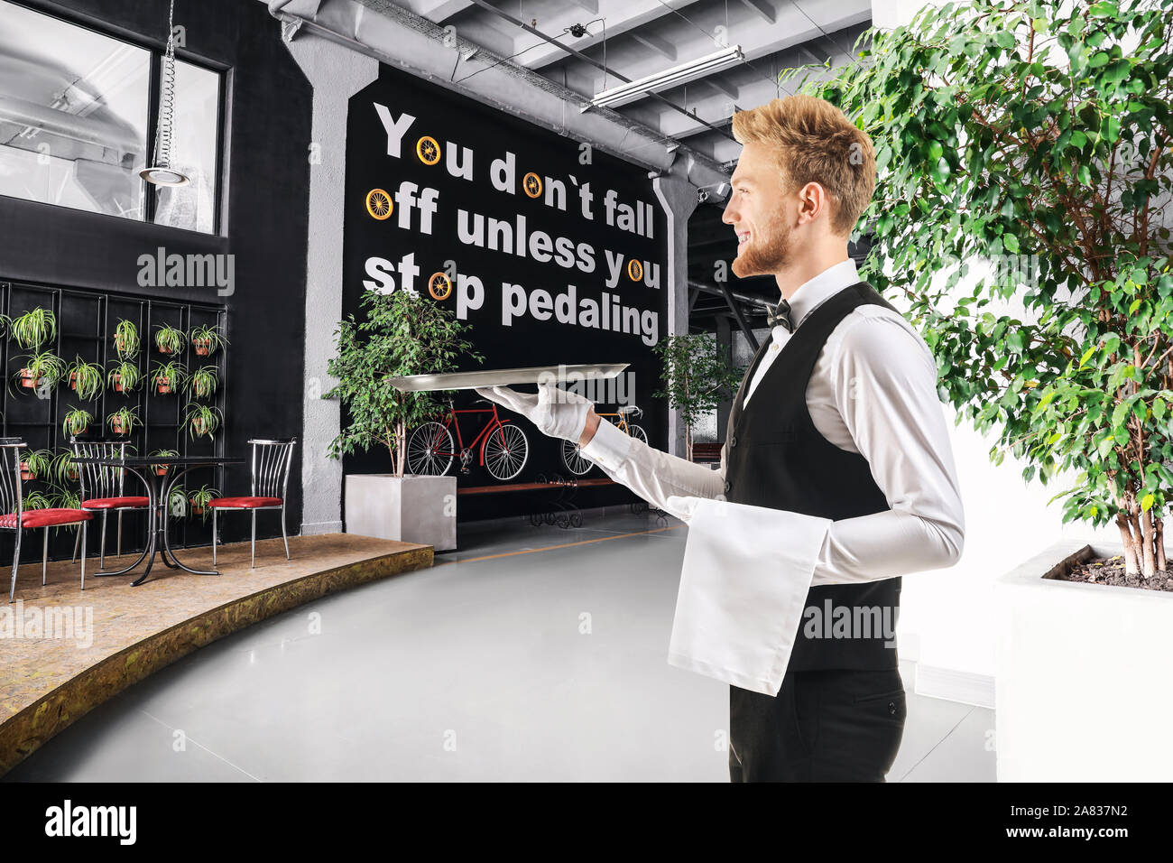 Handsome waiter with empty tray in modern cafe Stock Photo