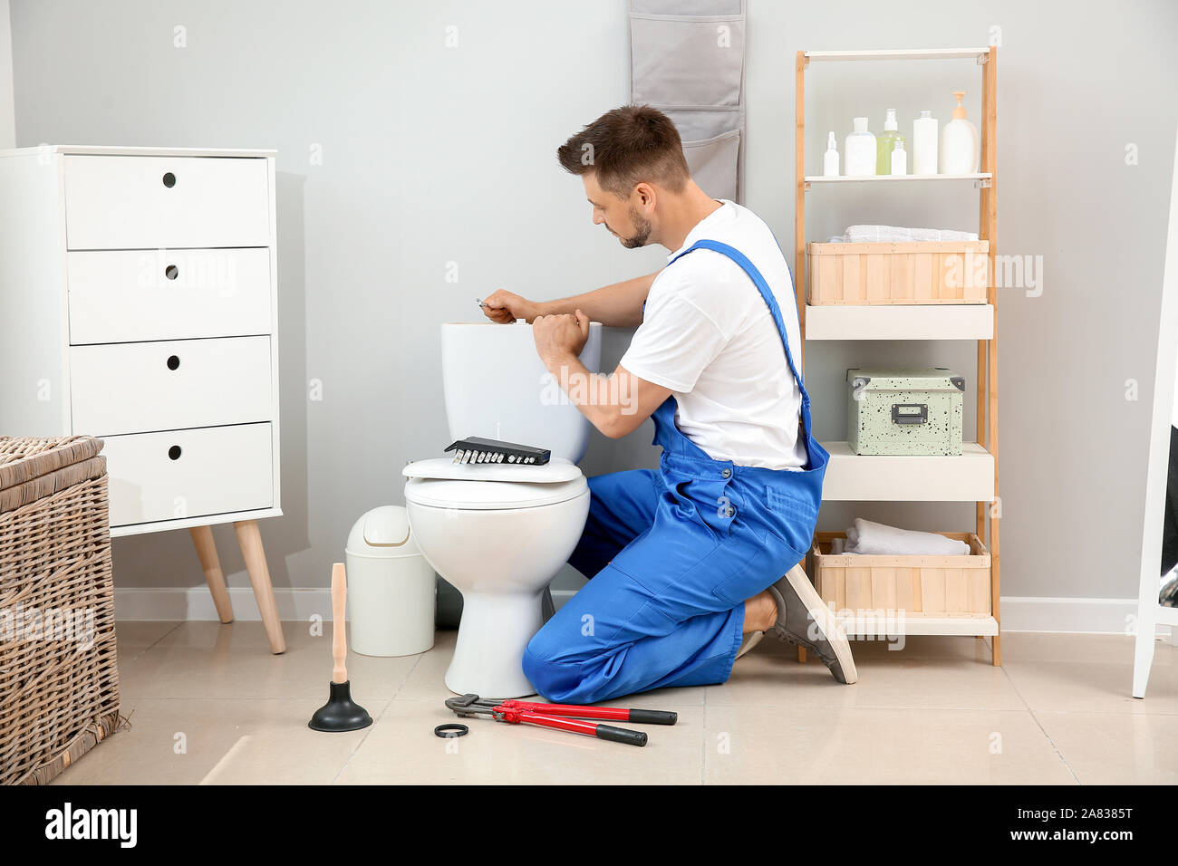 Plumber installing toilet in restroom Stock Photo Alamy
