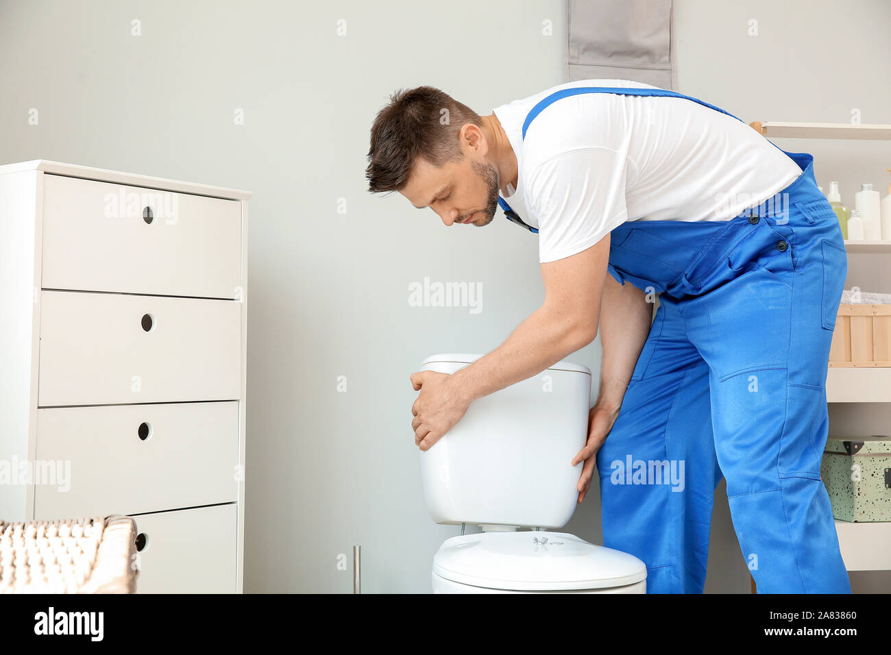 Plumber installing toilet in restroom Stock Photo Alamy