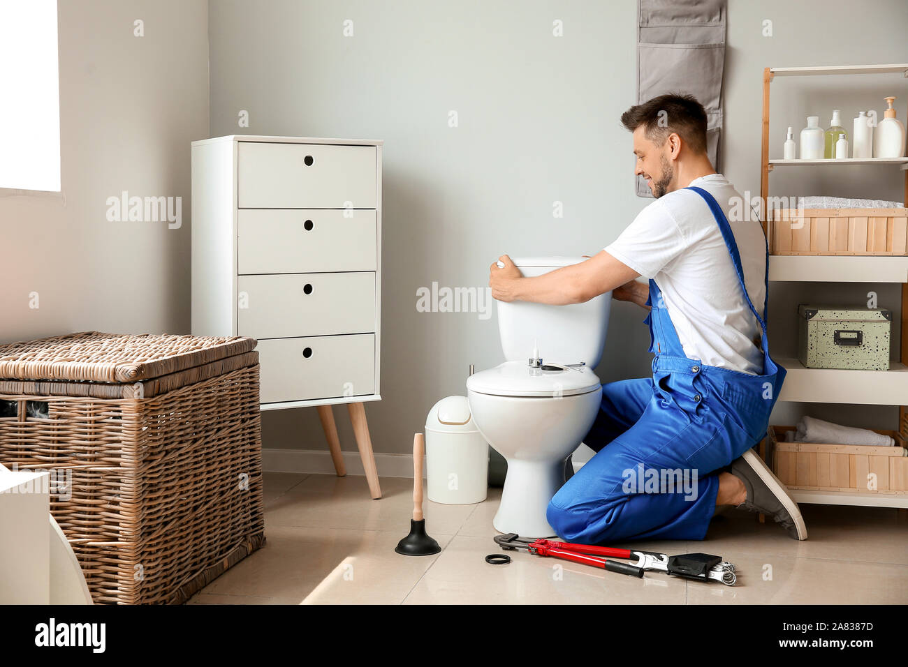 Plumber installing toilet in restroom Stock Photo Alamy