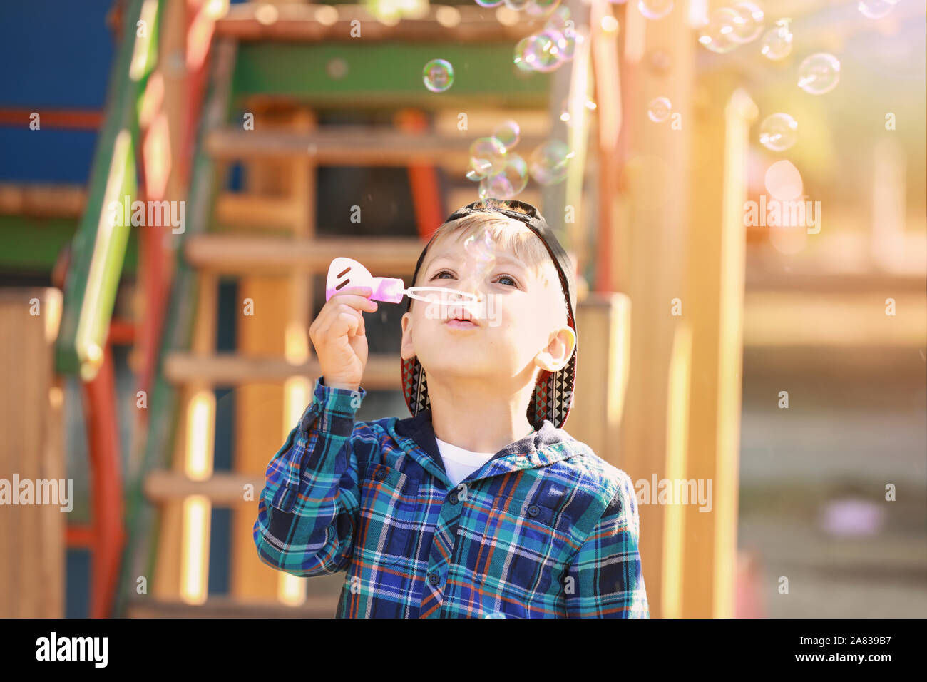 Cute little boy blowing soap bubbles on play ground Stock Photo - Alamy