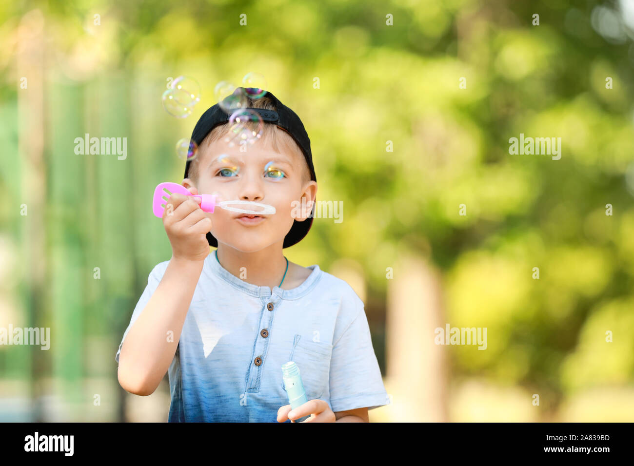 Cute little boy blowing soap bubbles in park Stock Photo - Alamy