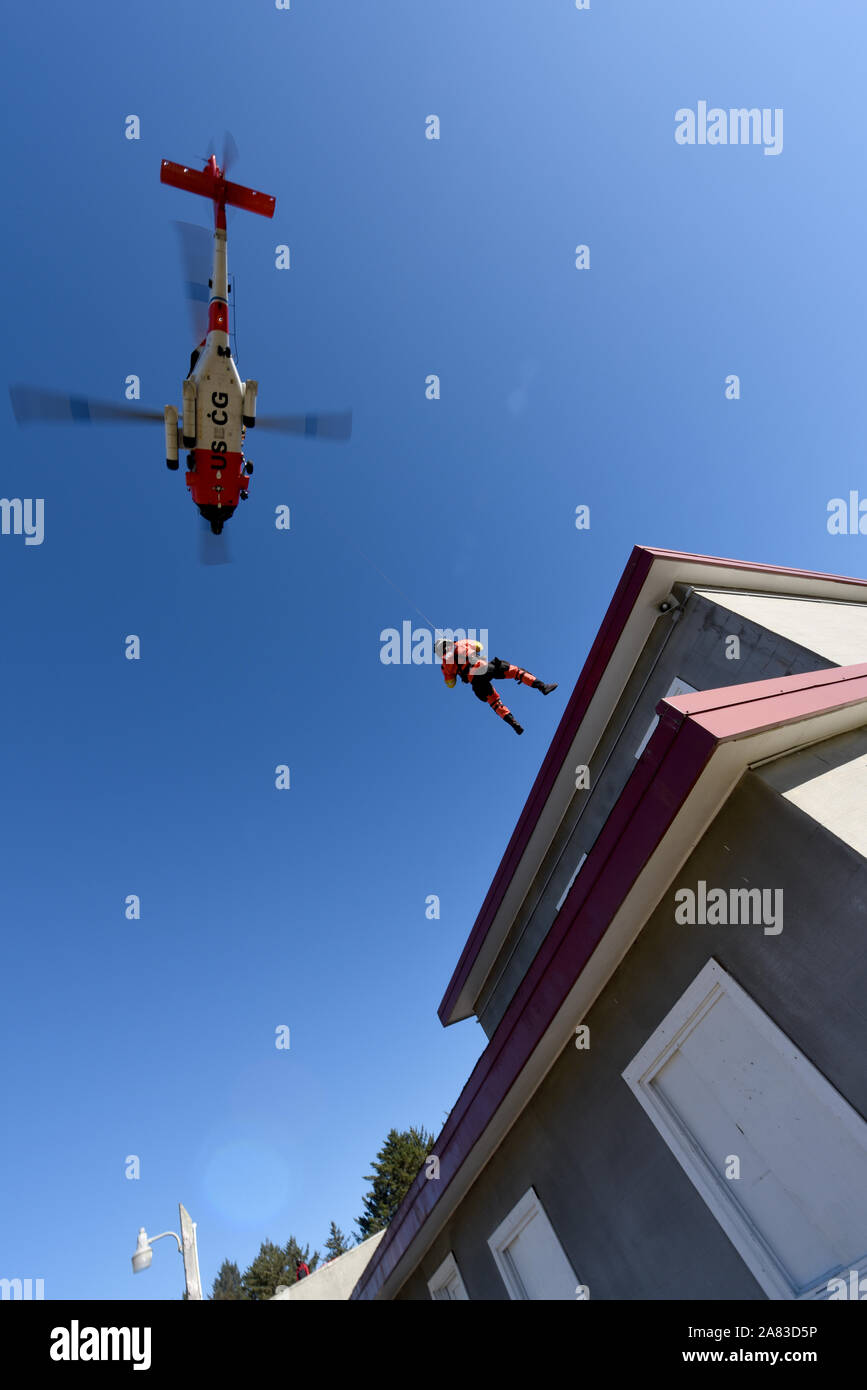 Petty Officer 3rd Class Bryan Evans, an aviation survival technician at Coast Guard Sector Columbia River, is lowered from an MH-60 Jayhawk helicopter to the roof of a simulated apartment building at the Camp Rilea Military Operations in Urban Terrain Village in Warrenton, Ore., Nov. 1, 2019. This training was designed to give search and rescue crews the needed experience to conduct urban airlifts. (U.S. Coast Guard photo by Petty Officer 3rd Class Trevor Lilburn) Stock Photo