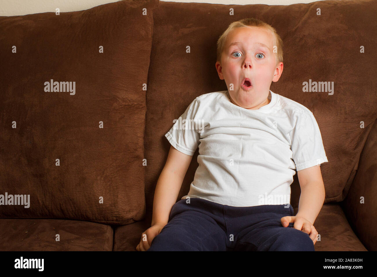 Kind on a couch making a funny surprised face Stock Photo