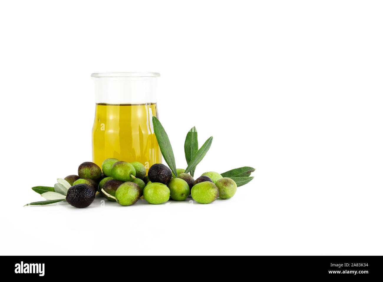 Glass bowl of fresh extra virgin olive oil and green olives with leaves ...