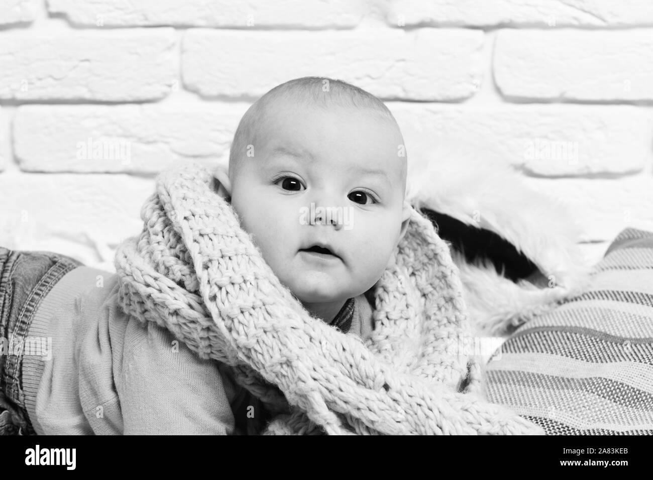 small baby boy with adorable curious face in yellow sweater laying on
