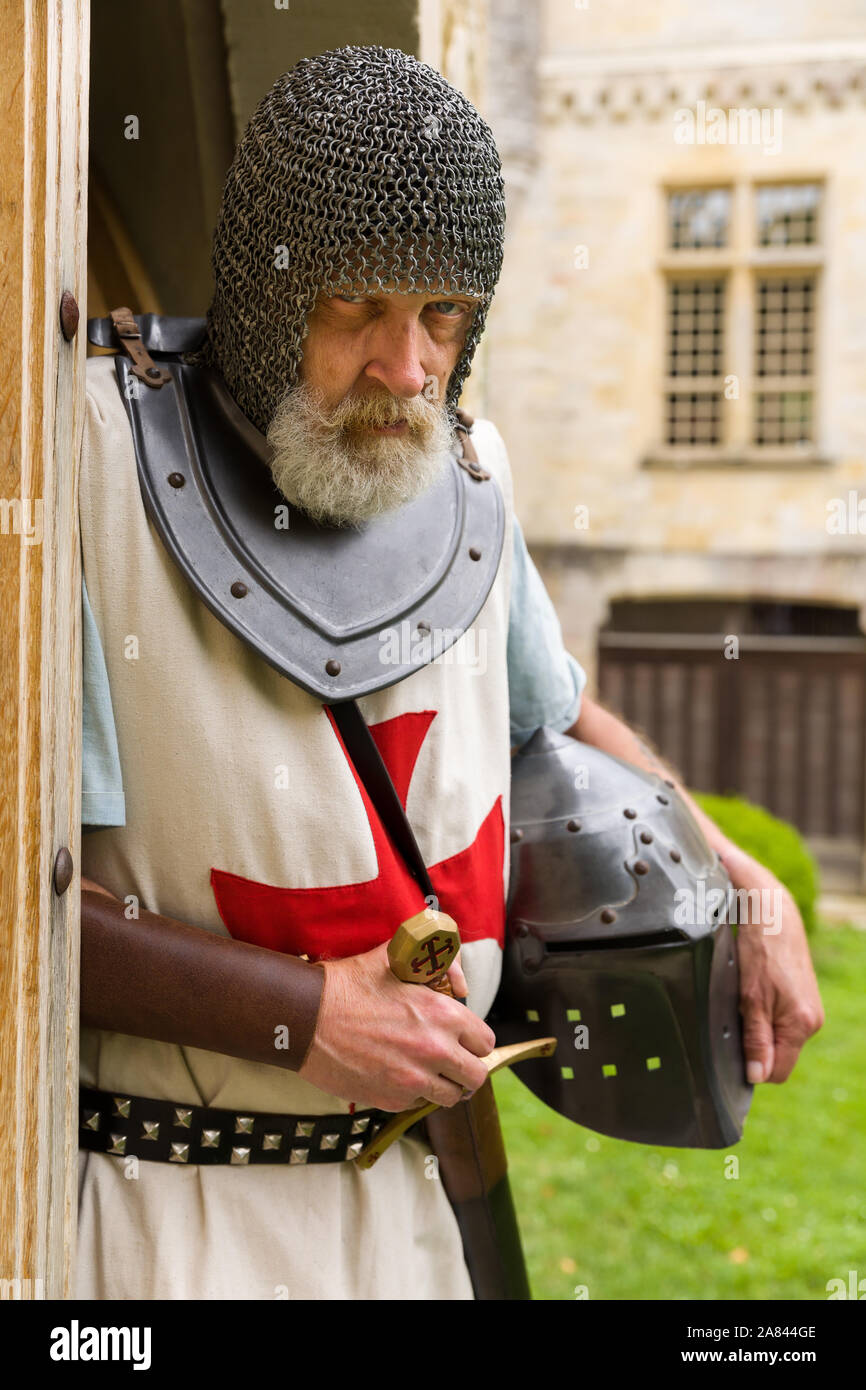 Outdoor pose of a man dressed in authentic Knight Templar outfit or crusader costume standing against a background of a medieval French castle Stock Photo