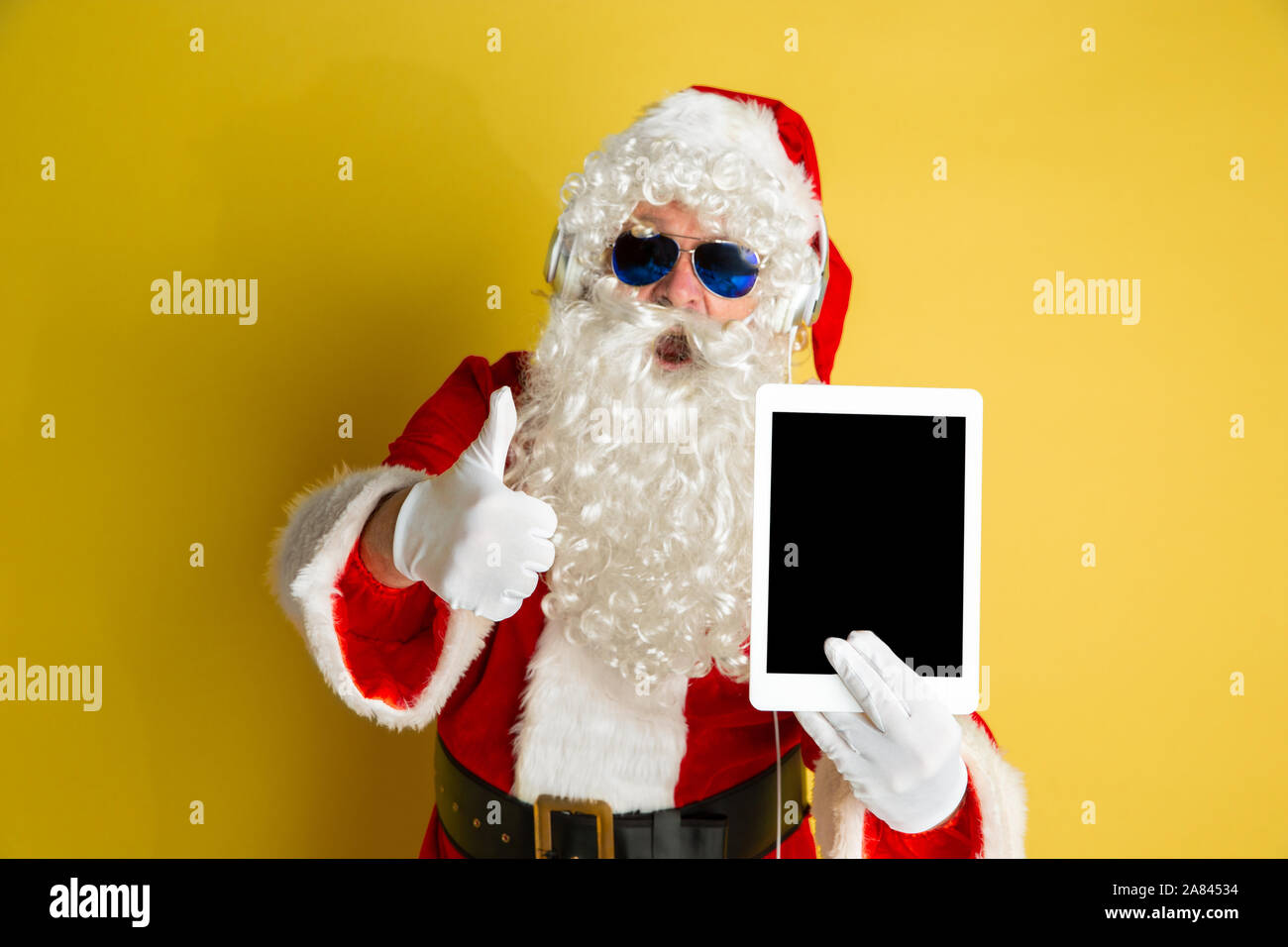 Santa Using Technology Image Santa Claus with modern gadgets isolated on yellow studio background ...