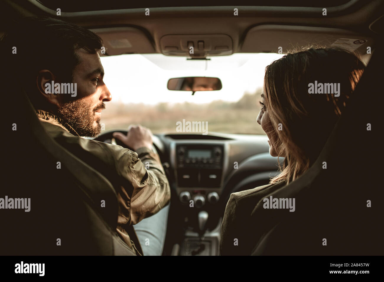 Happy couple in a car looking at each other. Back view. Stock Photo