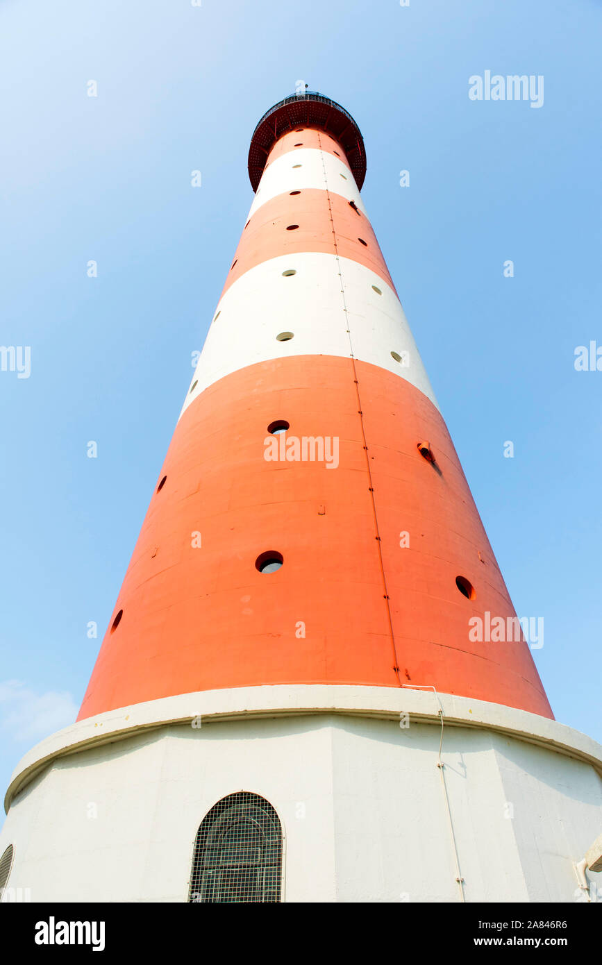 Red white striped lighthouse from the frog perspective in front of light blue sky Stock Photo