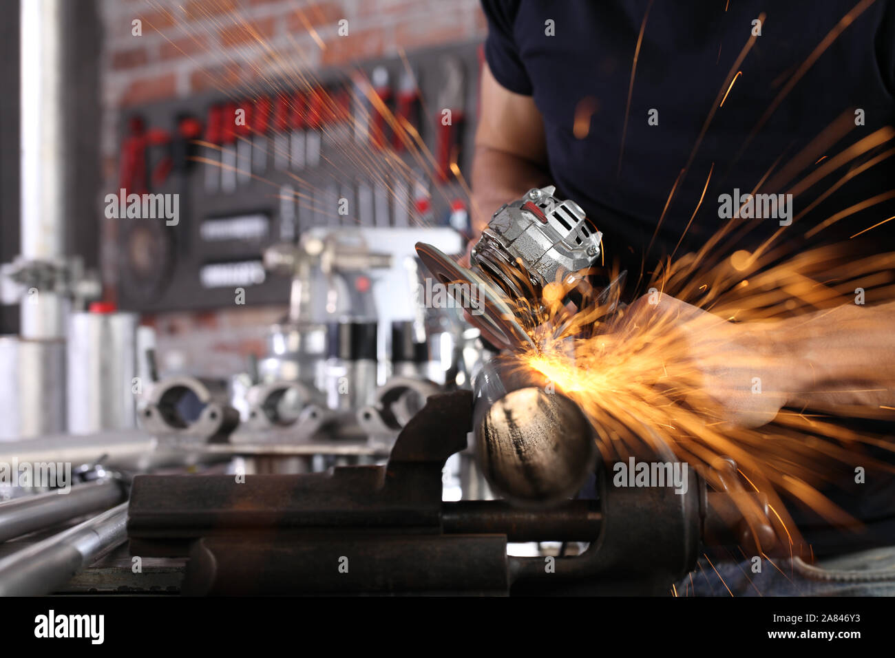 hands man work in home workshop garage with angle grinder, sanding metal makes sparks closeup, diy and craft concept Stock Photo