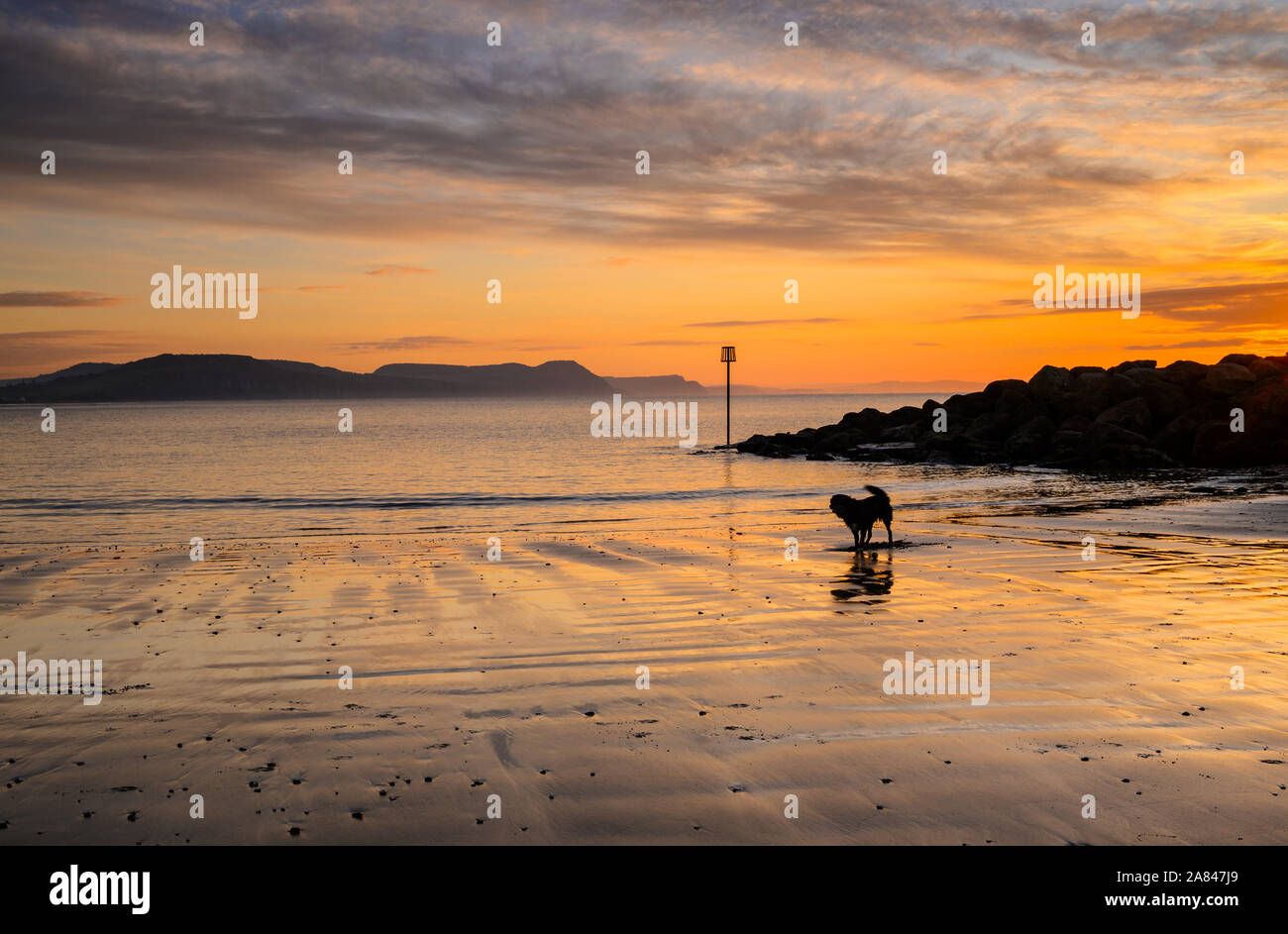 Lyme Regis, Dorset, UK. 6th November 2019. UK Weather: After a tranquil morning clouds start to gather over the Jurassic Coast heralding the arrival of unsettled weather. The early sunshine is reflected in the sand at low tide.  Credit: Celia McMahon/Alamy Live News. Stock Photo