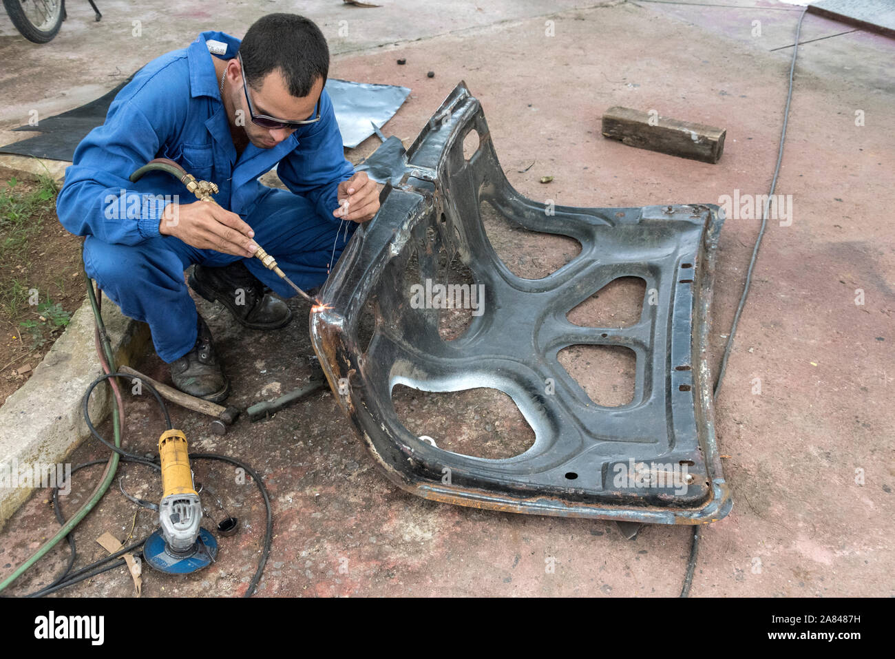 A Cuban car welder, welding a classic car part in a small village garage in the Valle de Vinales, Pinar del Río Province, west Cuba, Cuba Stock Photo