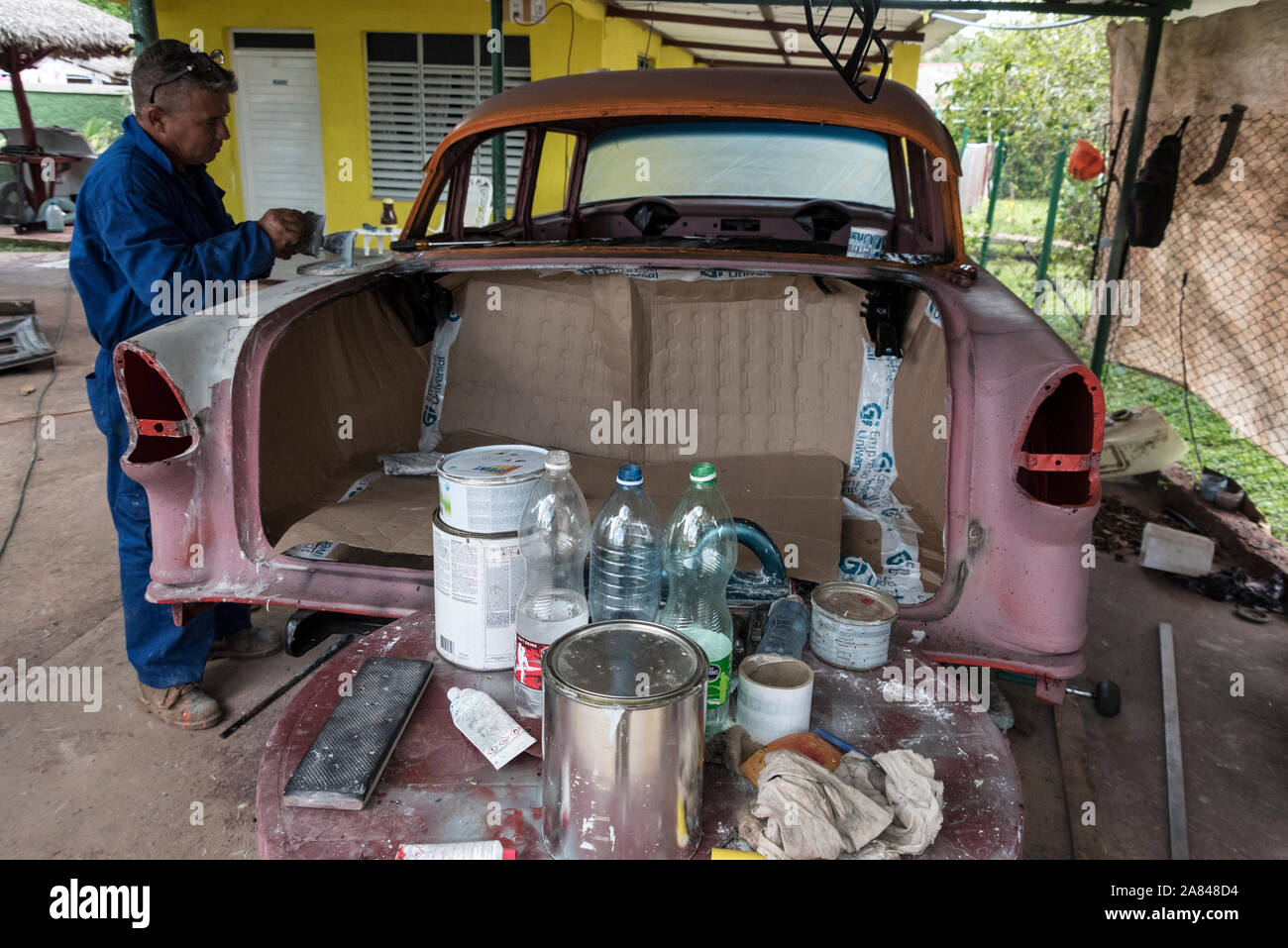 A Cuban car body repairer, working on a classic car in a small village garage in the Valle de Vinales, Pinar del Río Province, west Cuba, Cuba Stock Photo