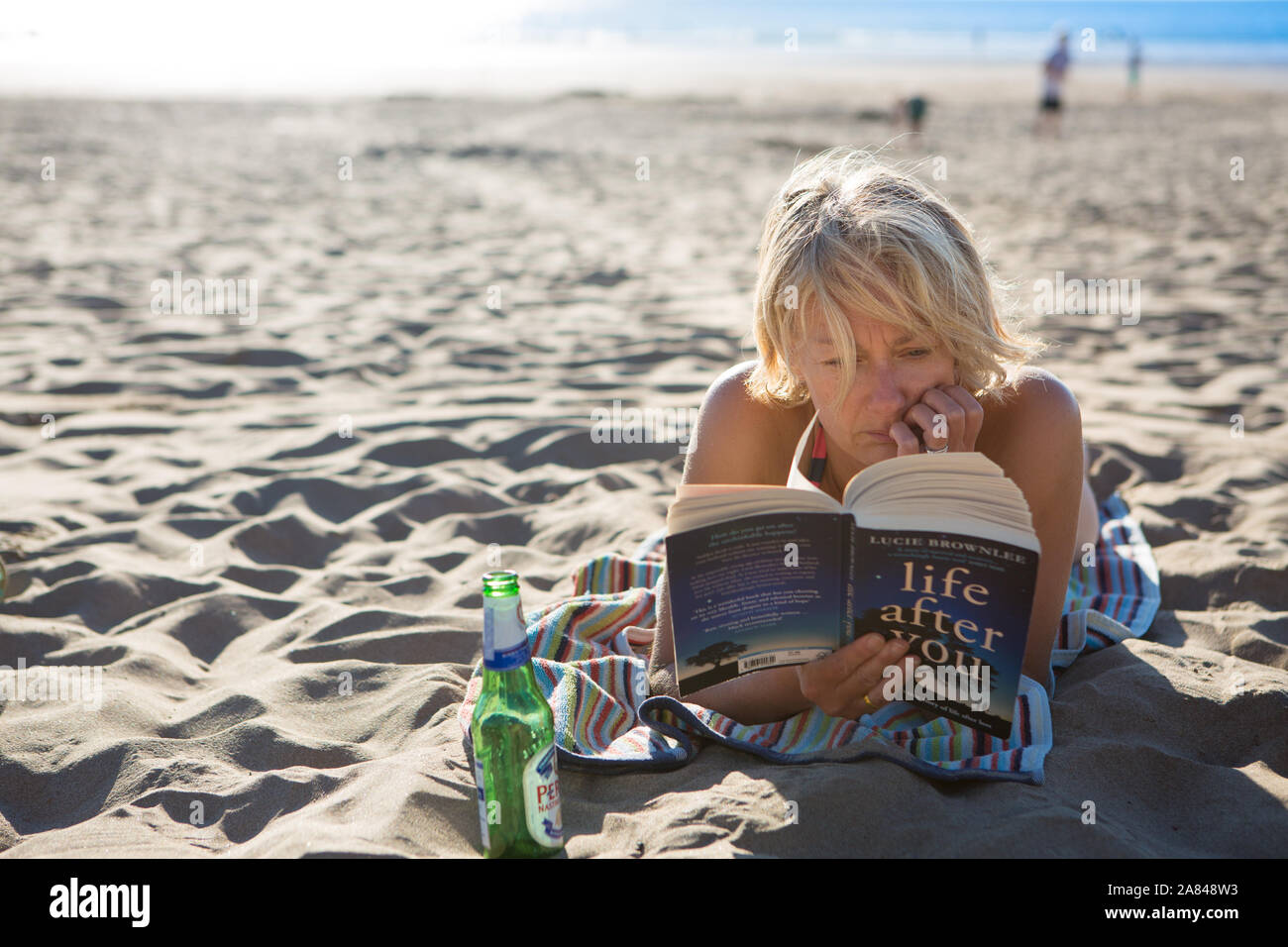 A young woman reading a book on the beach in summer, UK Stock Photo - Alamy