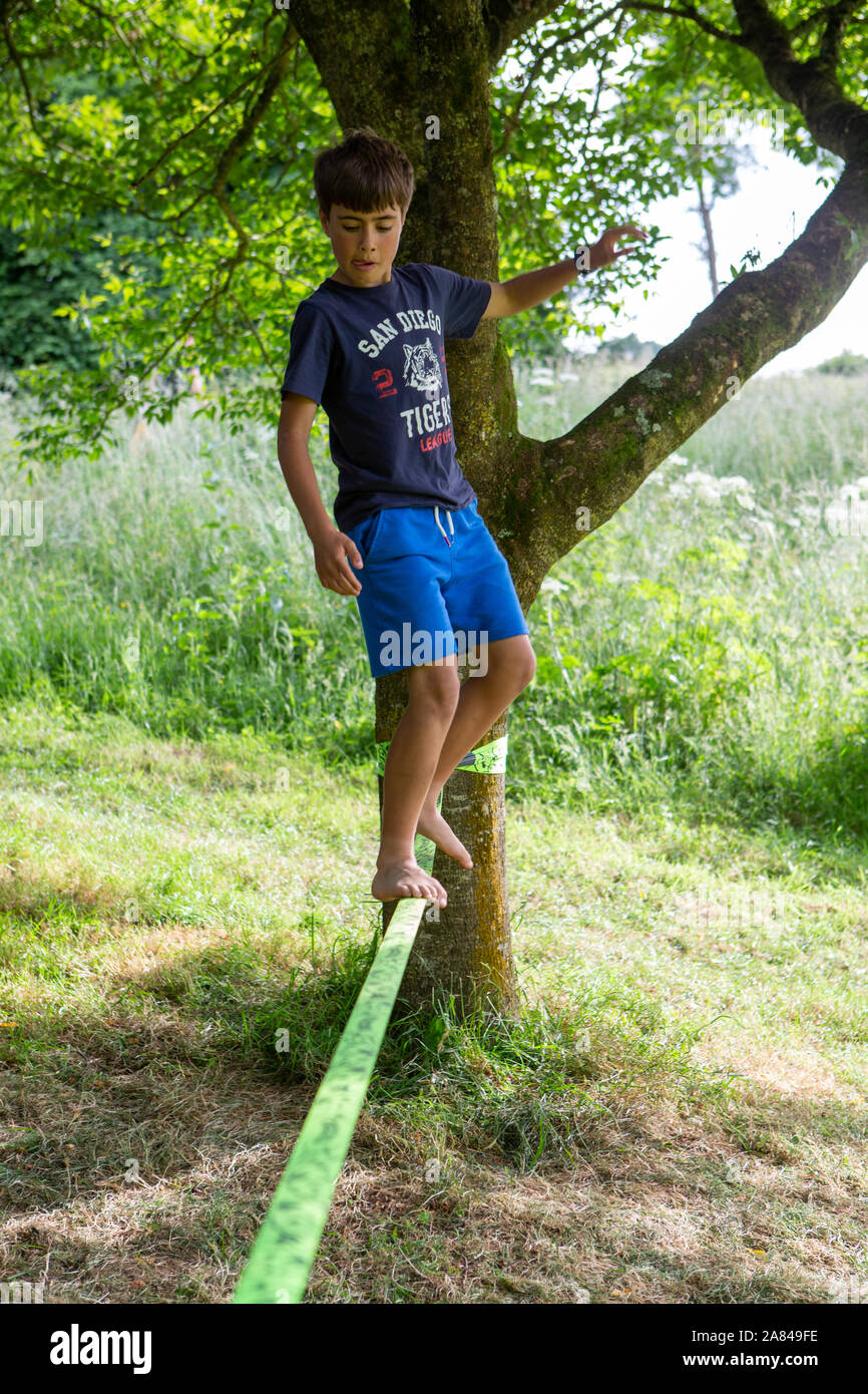 A young boy walks along a slack-line tied between two trees, UK Stock Photo  - Alamy